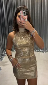 Vestido dorado de lentejuelas, corto y al cuerpo, con cuello halter.