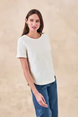 Remera blanca de manga corta con cuello redondo y bordados florales monocromáticos en relieve.