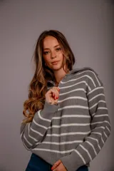Sweater de punto color beige con rayas horizontales blancas, cuello polo con cierre de cremallera y mangas largas.