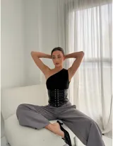 Corset negro de cuero sintético con cierre de cordones frontales y top asimétrico de un hombro.