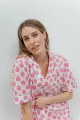 Conjunto de pijama de algodón a rayas verticales rosas y blancas, con detalles en celeste. Incluye camisa de manga corta con botones y bolsillo en el pecho, y shorts con cintura elástica.