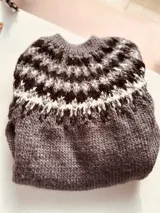 Sweater de punto color gris con guarda pampa en blanco y negro en la parte superior.