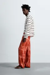 Pantalón relaxed fit de punto ligero tejido en hilatura de algodón color ladrillo con estampado a cuadros difuminados en blanco. Cintura elástica ajustable con cordón y bolsillos laterales.