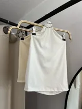 Top blanco de estilo halter con aro metálico en el cuello.
