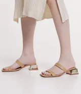 Sandalia mule color beige con dos tiras, puntera cuadrada y tacón bajo cuadrado cromado.