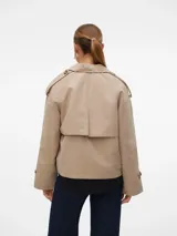 Trench corto color beige con doble botonadura, cuello de solapa invertida, manga larga con puños abotonados, bolsillos laterales y forro completo.