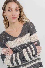 Sweater tejido calado a rayas horizontales anchas en color gris oscuro y crudo, con escote en V y corte recto.