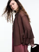 Camisa negra de lyocell y poliamida, con cuello clásico, mangas largas acampanadas con volados y cierre frontal con botones.