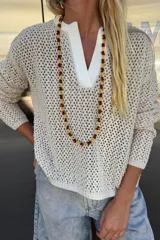 Buzo calado color crudo, tejido en algodón con cuello en V de color blanco.