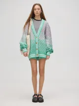 Cardigan tejido de punto con patrón de rombos en degradé de grises y blanco. Tiene corte oversize, mangas largas y cierre frontal con botones.