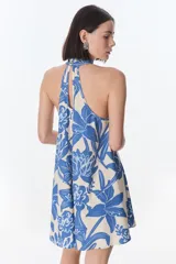 Vestido corto con estampado floral en tonos rojo y beige, cuello halter y corte evasé.