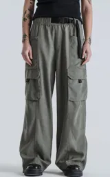 Pantalón cargo de silueta oversize, color gris oscuro/verde militar, con cintura elástica y cinturón de cinta negra ajustable con hebilla de plástico. Presenta bolsillos cargo amplios a los lados de las piernas.