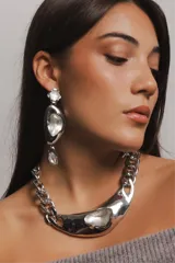 Collar metálico plateado estilo chunky con cadena de eslabones gruesos y dije central con forma de medialuna irregular con incrustación de cristal transparente.