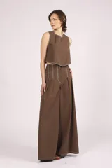 Pantalón negro de tiro alto, corte ancho y largo, con pliegues frontales y pespuntes contrastantes en blanco en la cintura y bolsillos.