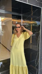 Vestido largo color amarillo pálido, con escote en V, mangas cortas abullonadas con detalle de calado y ruedo con volantes y calado.