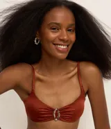 Top de bikini color ladrillo, de microfibra brillante, con breteles finos y adorno metálico en el centro del busto.