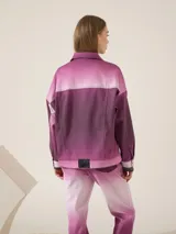 Campera trucker clásica de gabardina de algodón con elastano, con silueta oversize, hombro caído y largo hasta la cadera. Tiene estampa digital artesanal con degradé de colores.