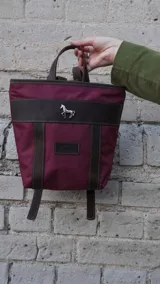 Mochila pequeña color borgoña con detalles en cuero marrón, asa de mano y correas ajustables.