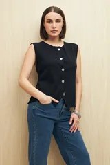 Chaleco de punto color beige, con cuello a la base y botones metalizados irregulares.