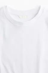 Remera blanca de algodón, corte amplio, con mangas cortas y cuello redondo.