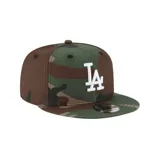 Gorra de béisbol con estampado de camuflaje en tonos verde, marrón y beige. Tiene el logo de los Dodgers bordado en blanco en el frente.
