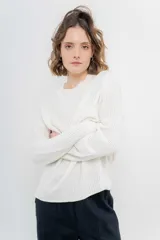 Sweater de punto color crema, de corte amplio, con cuello redondo y mangas largas.