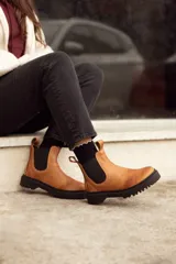 Bota de cuero color terracota, de caña media, con elásticos laterales y suela de goma negra.