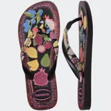 Ojotas Havaianas Top Tropicalia Vibes II, color negro con estampado de frutas tropicales y borde con patrón étnico. Las tiras son negras con el logo de Havaianas en dorado.