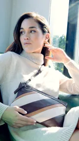 Sobre de mano de símil cuero con diseño de franjas diagonales en negro, blanco y marrón. Cuenta con cierre metálico frontal, bolsillo interior con cierre y otro abierto con división. Incluye correa desmontable para usar como bandolera.