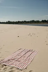 Pareo rectangular con estampado a cuadros en tonos celeste, naranja y blanco, con detalle de flecos en los bordes.