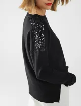 Buzo de tejido de punto color negro, con cuello redondo y mangas largas. Apliques de lentejuelas en los hombros. Marca Q2.