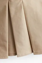 Top corto color beige de algodón con escote en V y breteles spaghetti. Modelo ceñido con cierre lateral oculto y pliegues de caja alrededor de la cintura formando un peplum. Forrado.