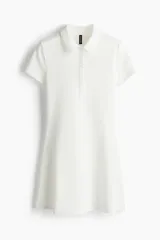 Vestido corto blanco de piqué con cuello polo, tapeta de botones y falda acampanada.