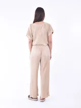 Pantalón de vestir color beige claro, de corte palazzo y tejido plisado.