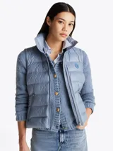 Chaleco acolchado celeste con cuello alto, cierre frontal con cremallera, dos bolsillos laterales con cremallera y logo de la marca en el pecho. Tiene mangas de tejido de punto. Repele el agua y tiene relleno de plumón.