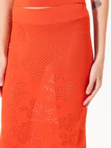 Pollera larga tejida color naranja, de corte ajustado y calados.
