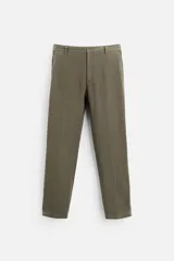Pantalón de vestir color verde oliva, confeccionado en tejido de lino. Corte recto, tiro medio, con bolsillos laterales y traseros de ojal. Cierre frontal con cremallera y botón.
