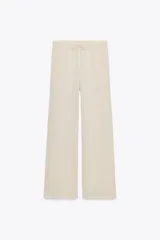 Pantalón de punto color beige, de tiro alto con cintura elástica ajustable con cordones y corte ancho.