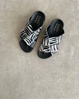 Sandalias Lucy in the Sky con estampado de cebra, tiras cruzadas y suela plana.