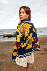Sweater de lana tejido y bordado a mano con calce holgado, cuello a la base y puños. Diseño con rayas horizontales en azul y amarillo, y bordados de flores multicolores. Talle único, similar a un M/L.