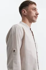 Camisa azul de manga larga con cuello mao y cartera abotonada.