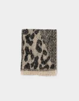 Bufanda tejida de lana en tonos beige y negro, con estampado geométrico y terminación en flecos.