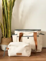 Bolso maternal de lona de algodón color crema, con detalles en marrón y azul, impermeable y con avíos personalizados.