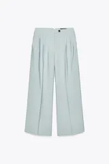 Pantalón de tiro medio color celeste confeccionado en hilatura con mezcla de lyocell. Tiene bolsillos laterales, pinzas delanteras, pierna ancha y cierre frontal con cremallera y botón.