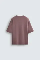 Camiseta color marrón con costura curva en el frente, corte holgado, cuello redondo y mangas cortas.