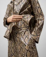 Sobrecamisa de poliuretano con estampado de piel de serpiente en tonos marrones y negros. Tiene cuello bowling, cierre con botones, manga larga con puños abotonados y forro de algodón.