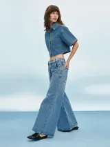 Camisa de denim celeste con corte cropped, mangas cortas y bolsillo en el pecho.