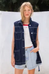 Chaleco negro de jean con cuello camisero, sin mangas, con cierre frontal abotonado y bolsillos delanteros.