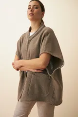 Chaleco color crema de lana sin teñir, corte recto, con cuello y solapa pronunciadas, broches a presión y bolsillos ojal.