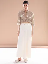 Pantalón ancho de tiro alto con dos botones en la parte frontal, confiriendo un estilo elegante y moderno.